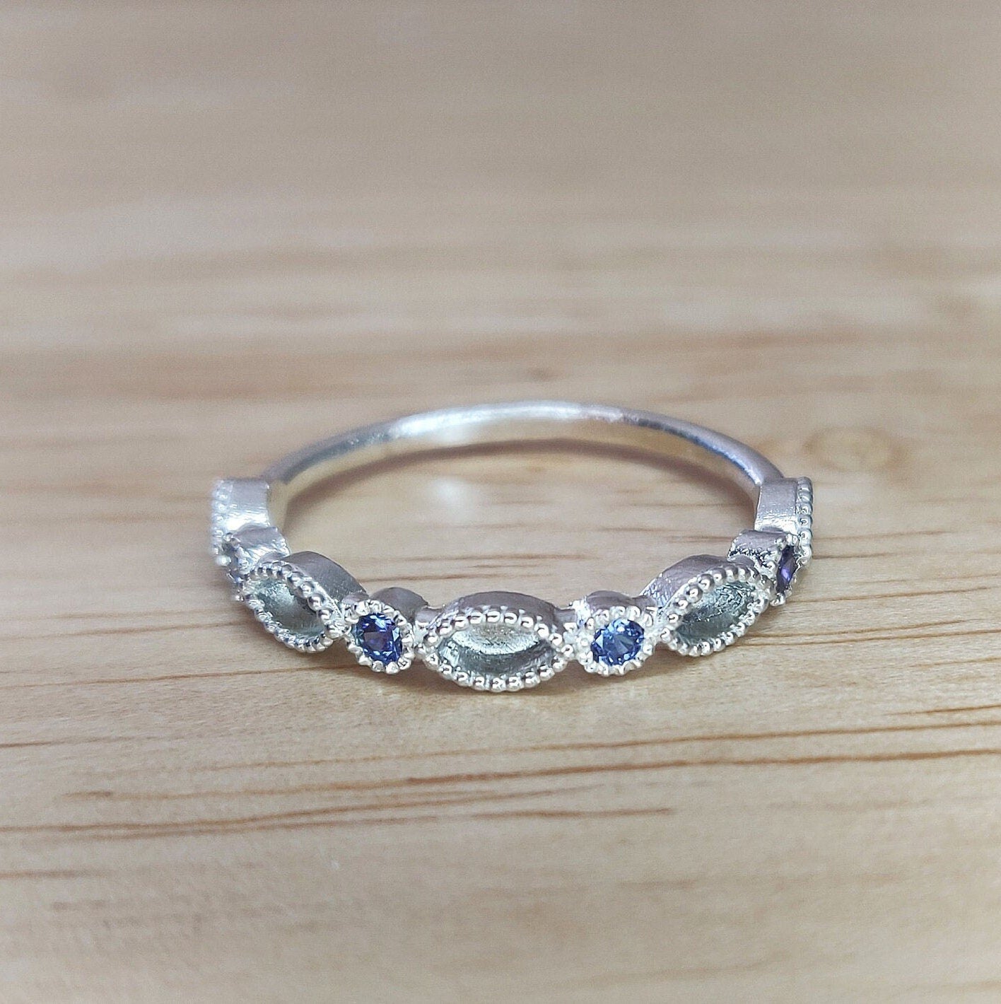 Sapphire Marquise and Brilliant cut stone eternity ring on a wooden background.