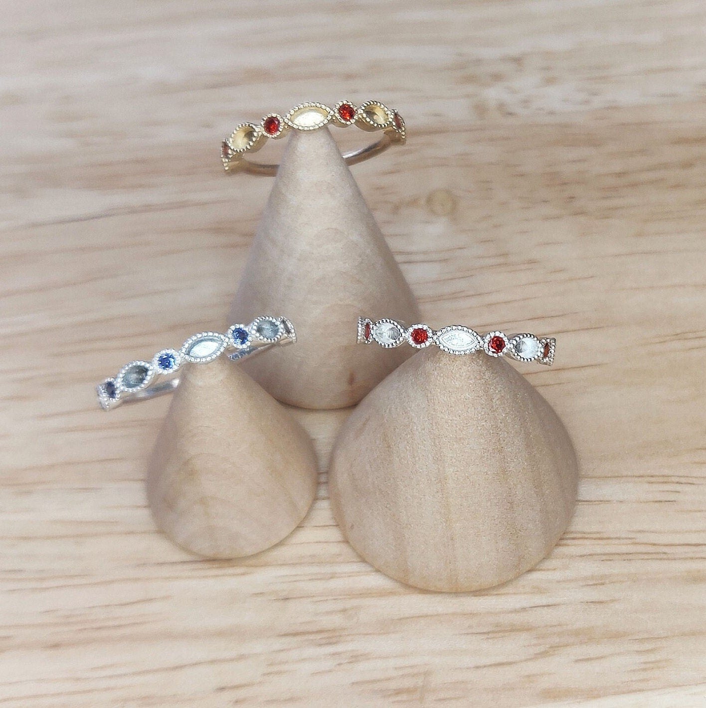 Gold and Silver Ruby and Sapphire eternity rings being displayed on wooden cones.