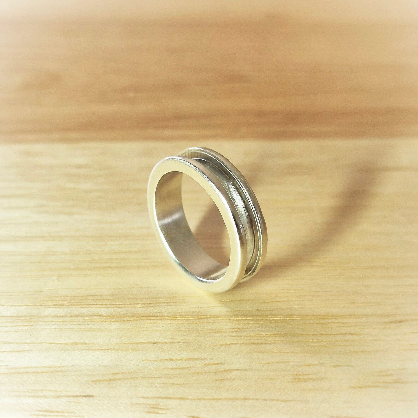 Profile View of a Silver Channel Ring on a Wooden Desk