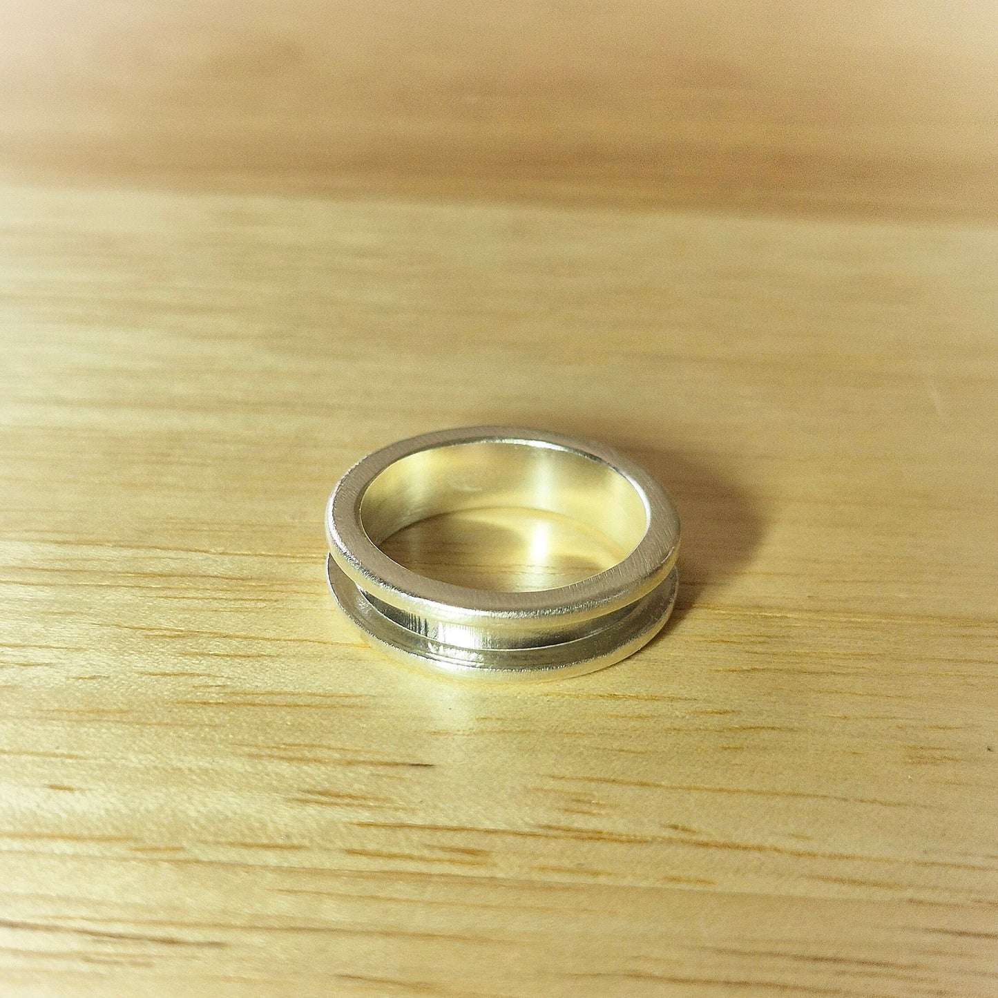 Top View Of A Silver Channel Ring on a Wooden Background.