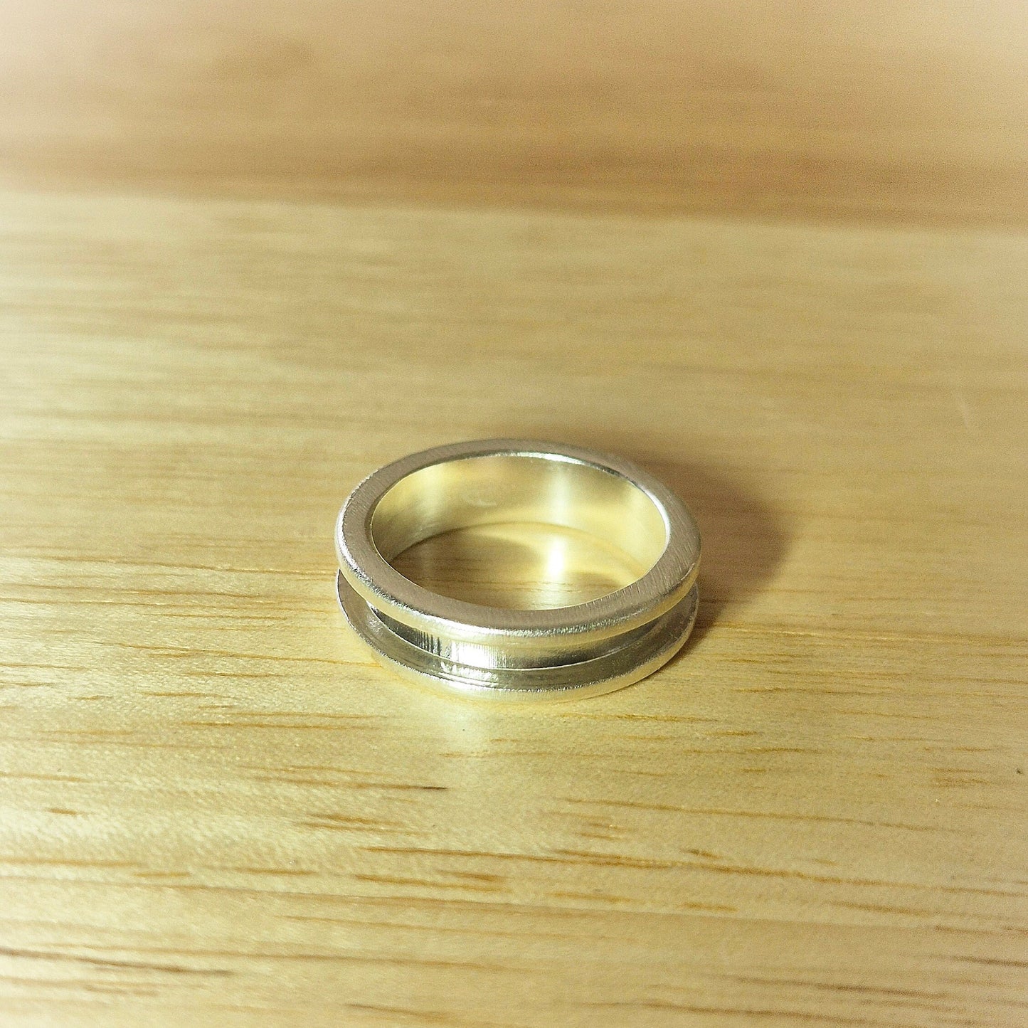 Top View Of A Silver Channel Ring on a Wooden Background.