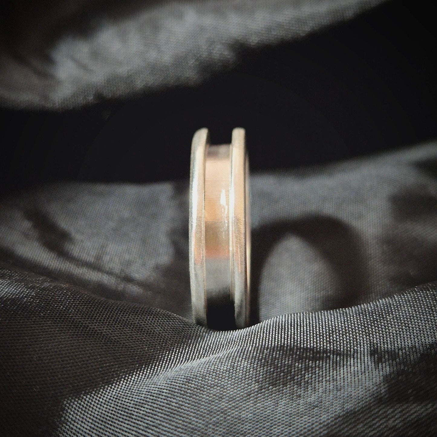 Side View Of A Silver Channel Ring on a Black Sheet