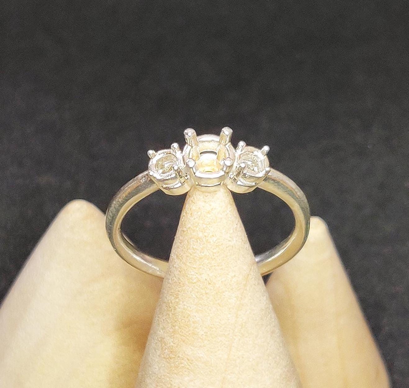 Top view of a 3 stone sterling silver ring with prong settings on a cone