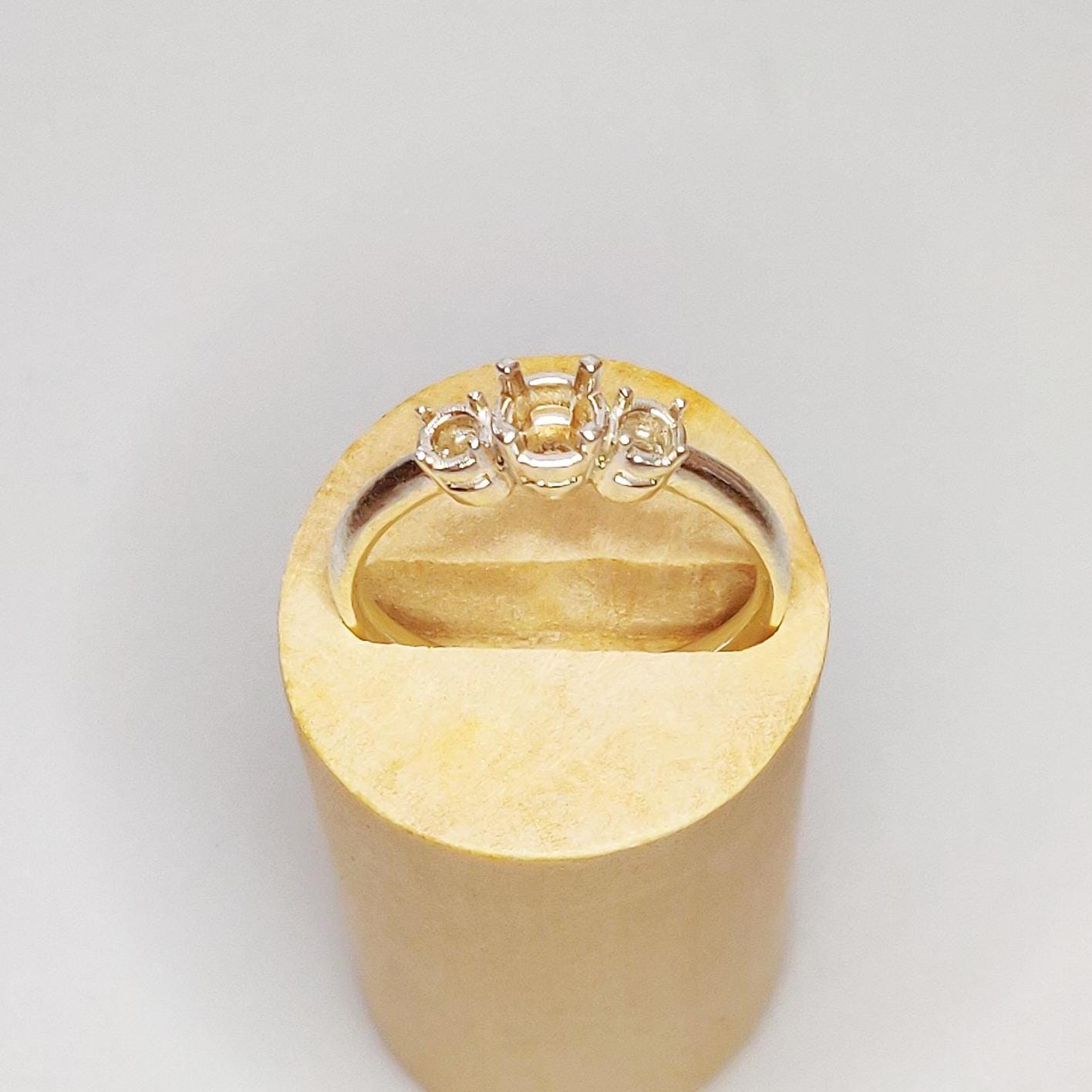 Ring blank with space for three round stones in a wooden display.