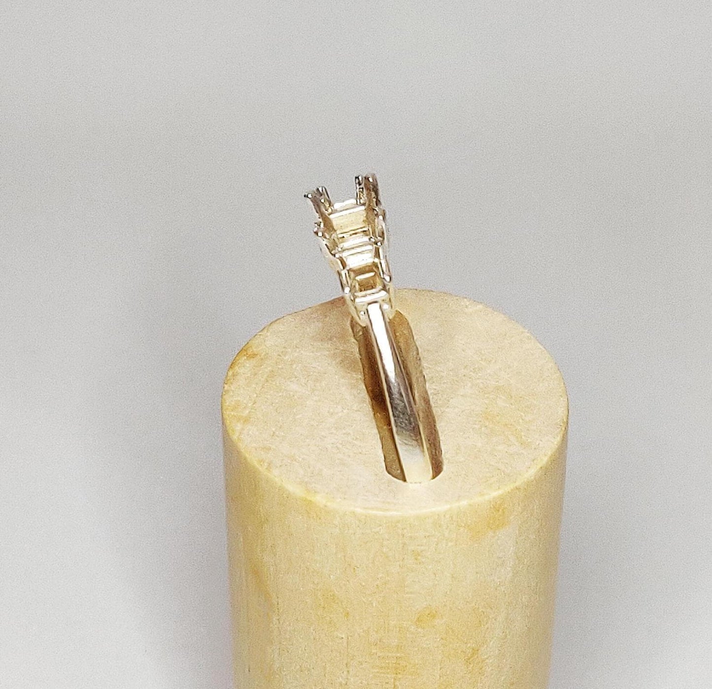 Silver ring in a wooden block at a jaunty angle.
