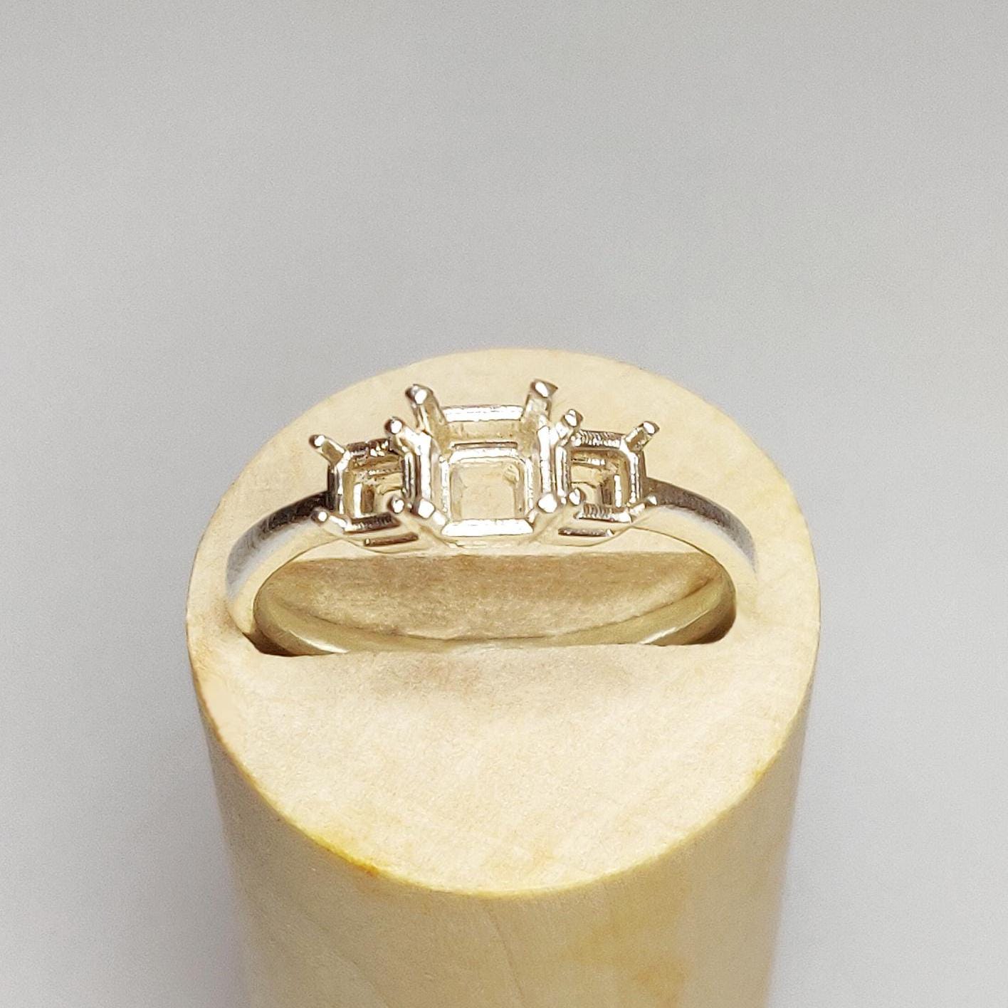 Top view of a silver 3 stone ring blank in a wooden display block.