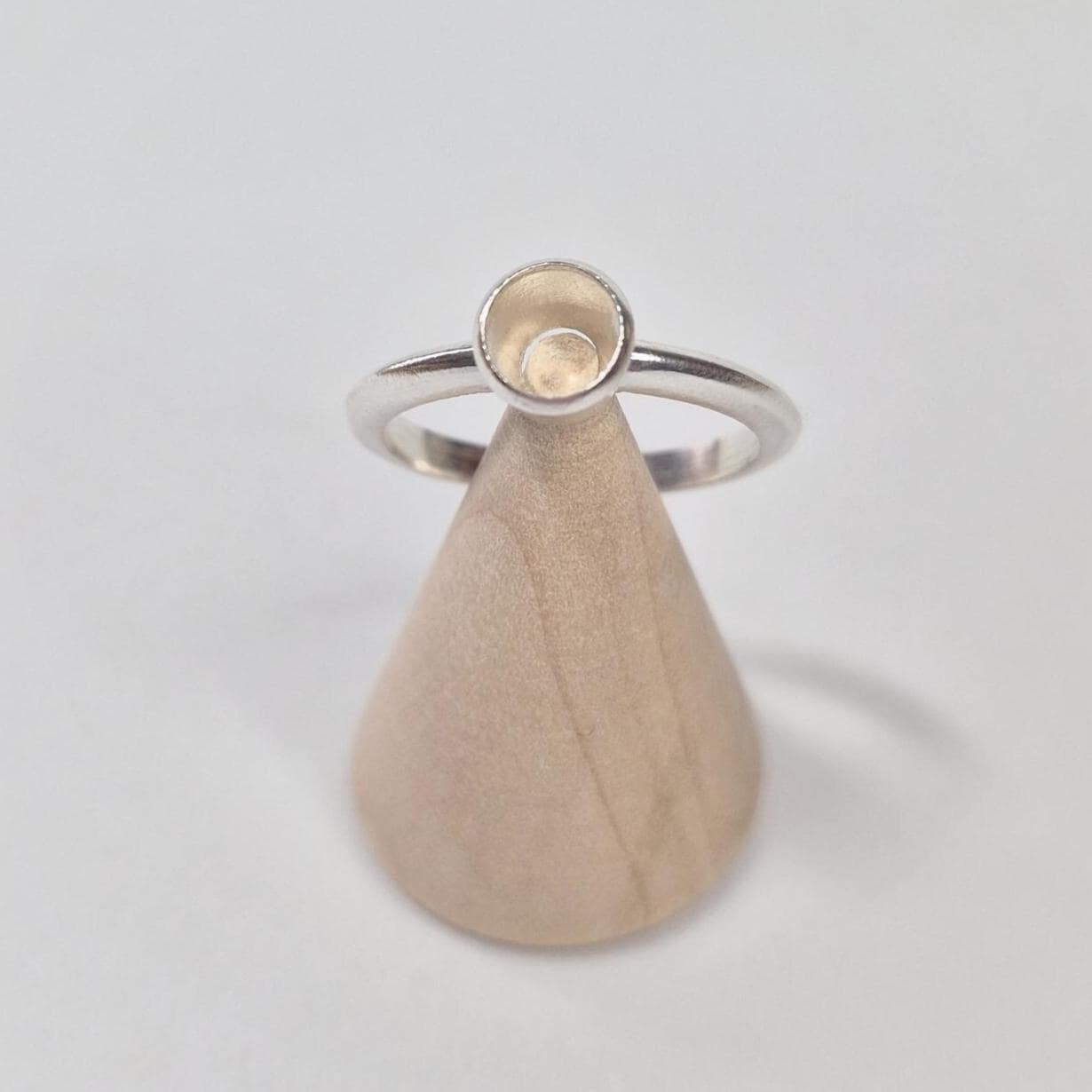 Top View of a Silver Rubover Setting Ring on a Wooden Cone
