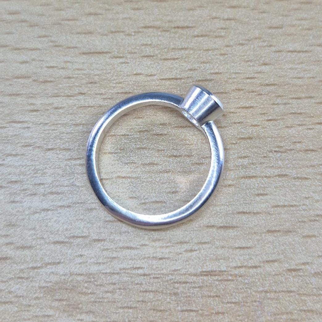 Through Ring View of a Silver Rubover Setting Ring on a Wooden Background.