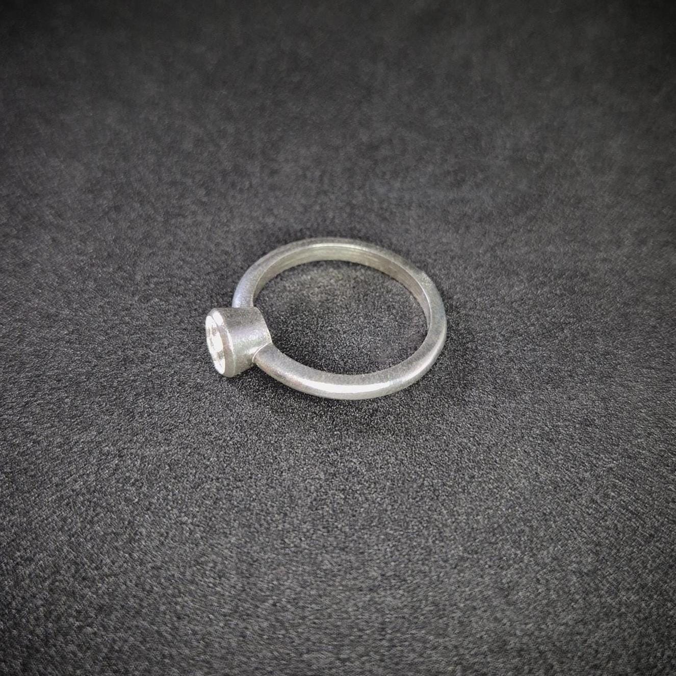 Left View of a Silver Bezel Ring on a Dark Background.