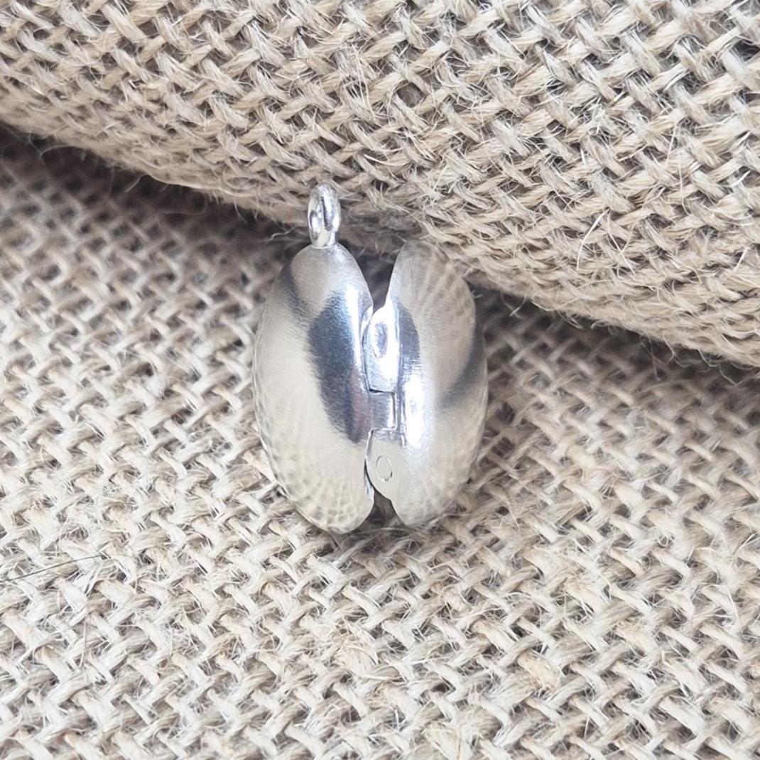 Rear View of an Open Round Silver Locket Against a Jute Background.