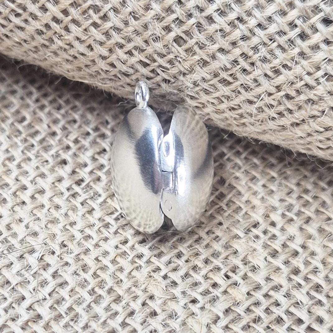 Rear View of an Open Round Silver Locket Against a Jute Background.