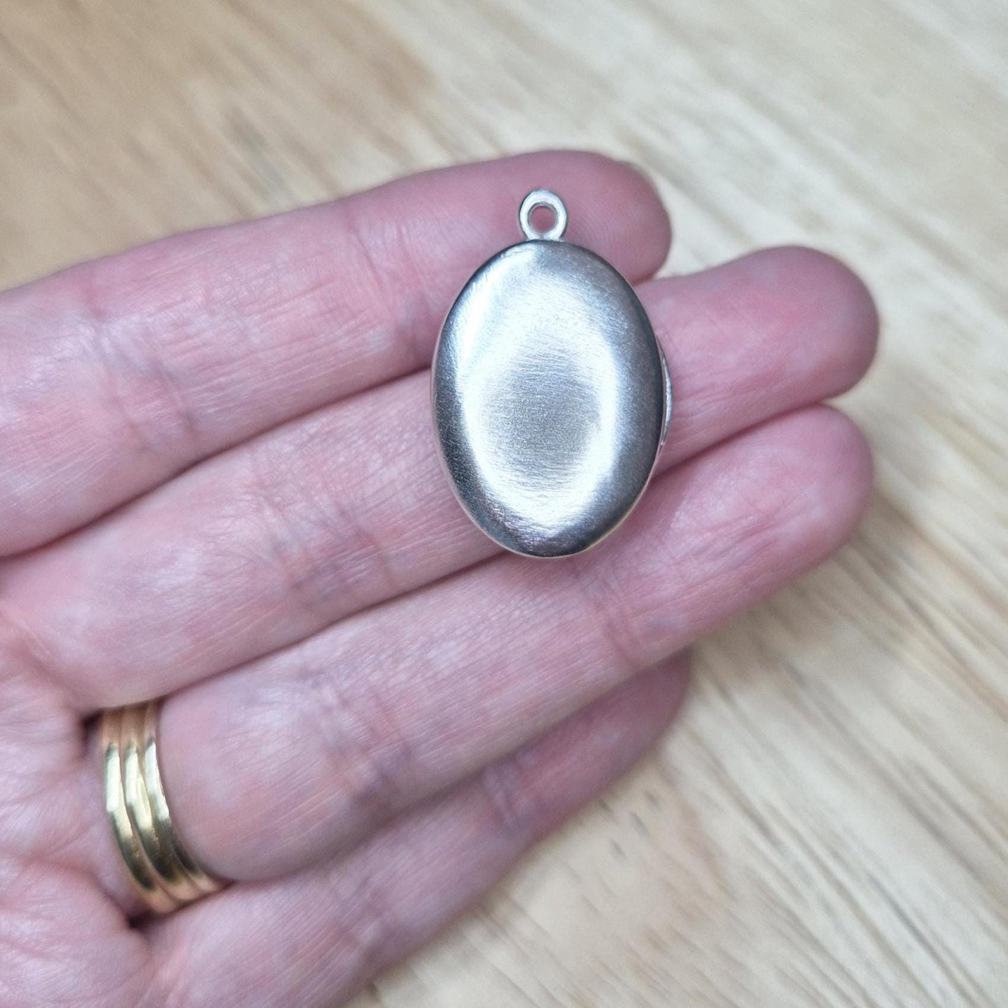 Oval Silver Locket Being Held in a Hand.