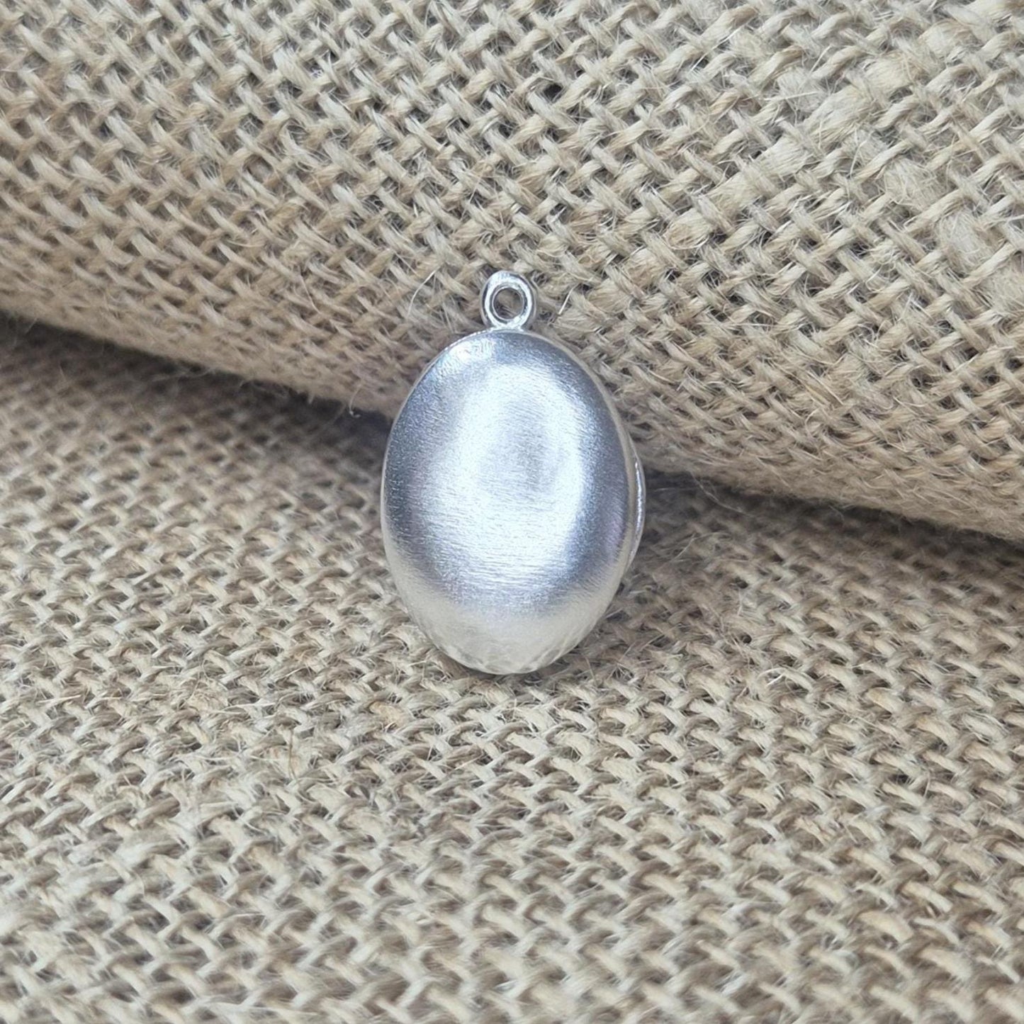 Closed Oval Silver Locket Against a Cloth Background.