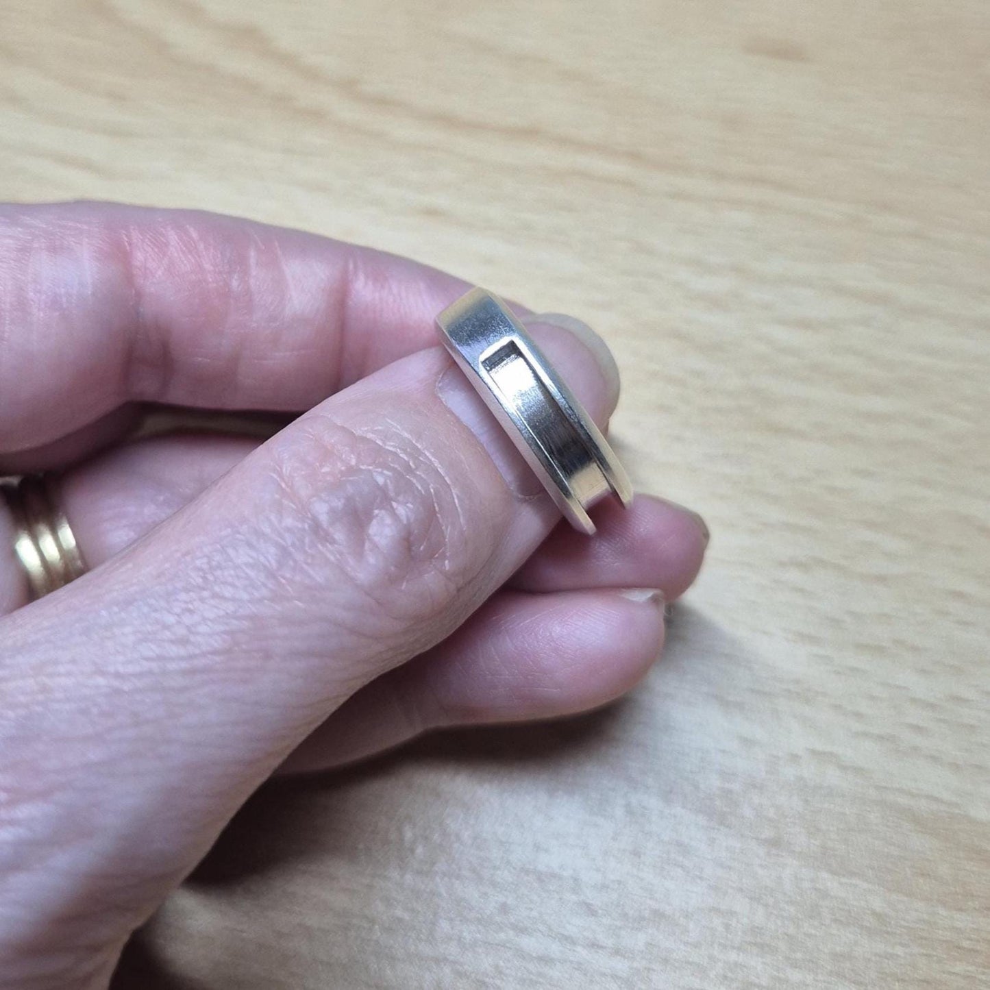 Side view of a half channel silver ring held between fingers, showing the recessed groove ideal for channel setting or inlay work.