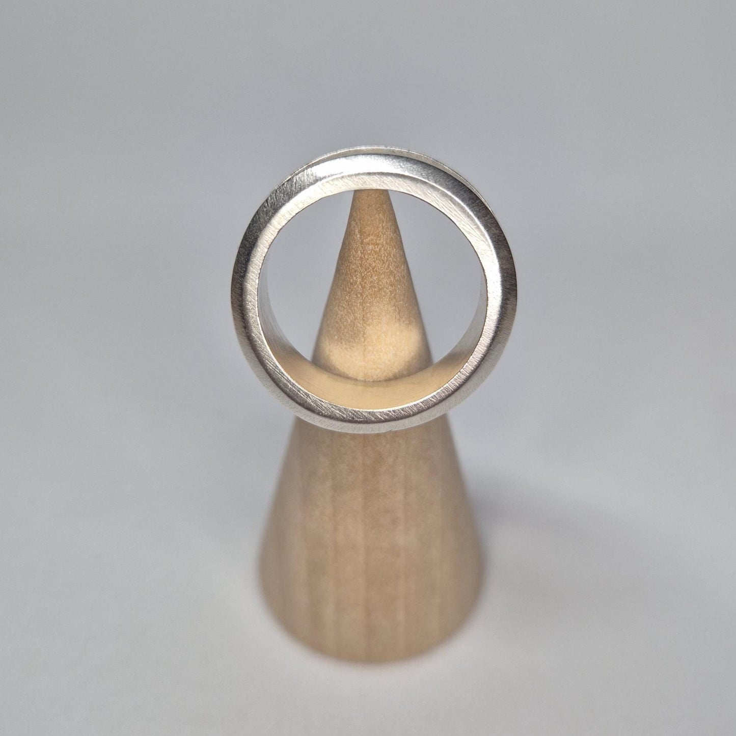 Straight-on view of a half channel ring balanced vertically on a cone, with the full circular band clearly framed.