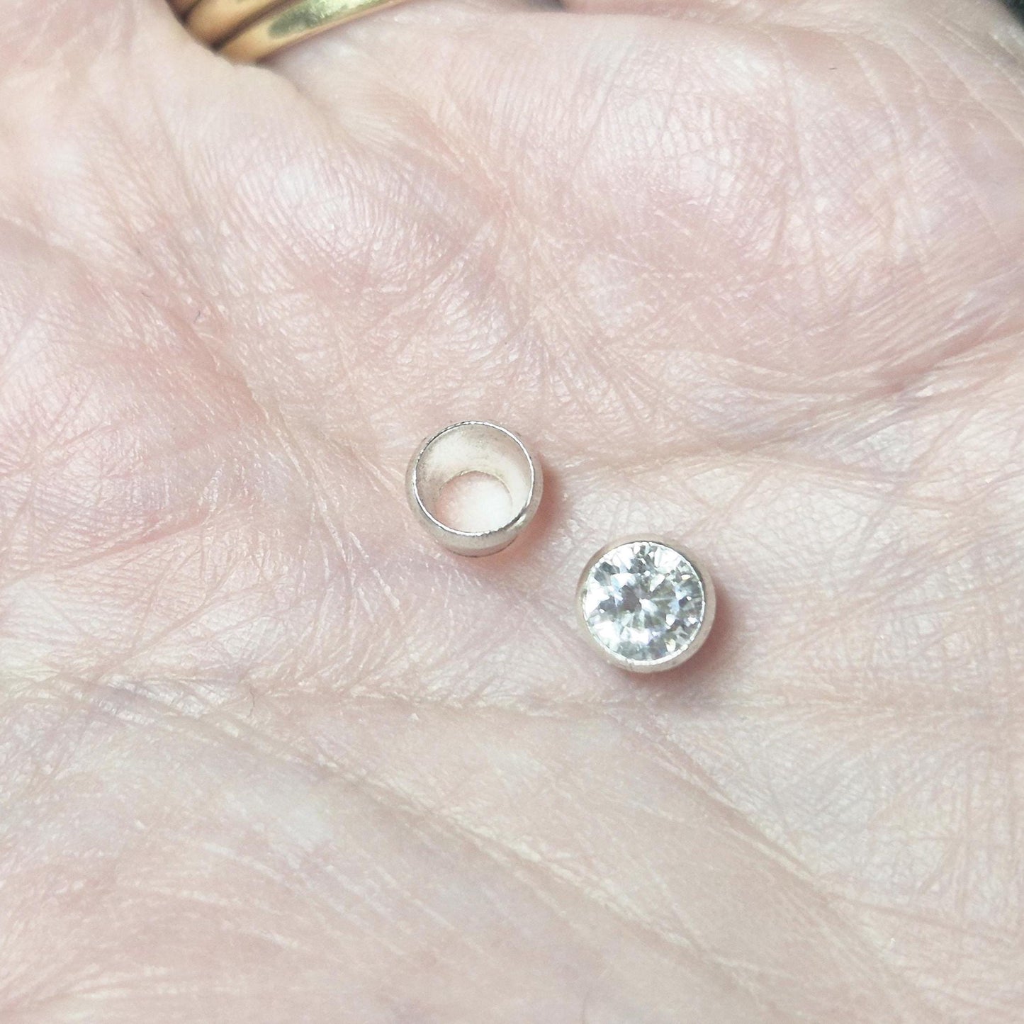 Sterling silver 5mm gemstone setting and mounted stone displayed on hand for scale reference in jewellery use.