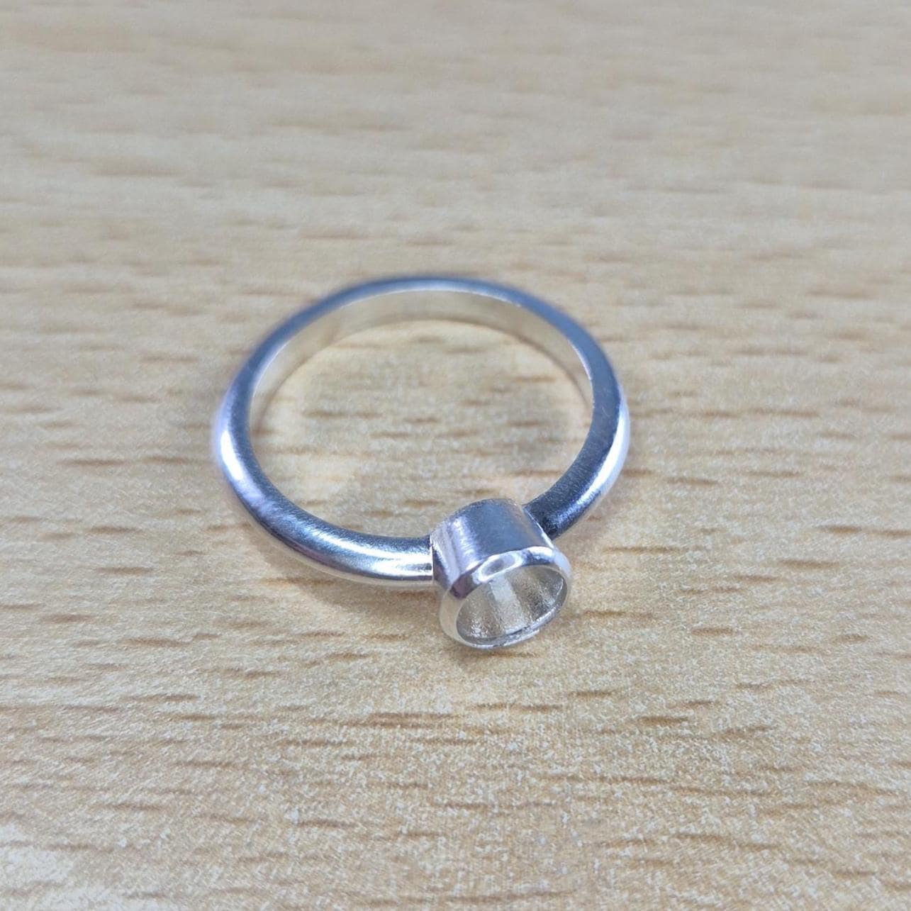 Silver Open Bezel Ring on a Wooden Background