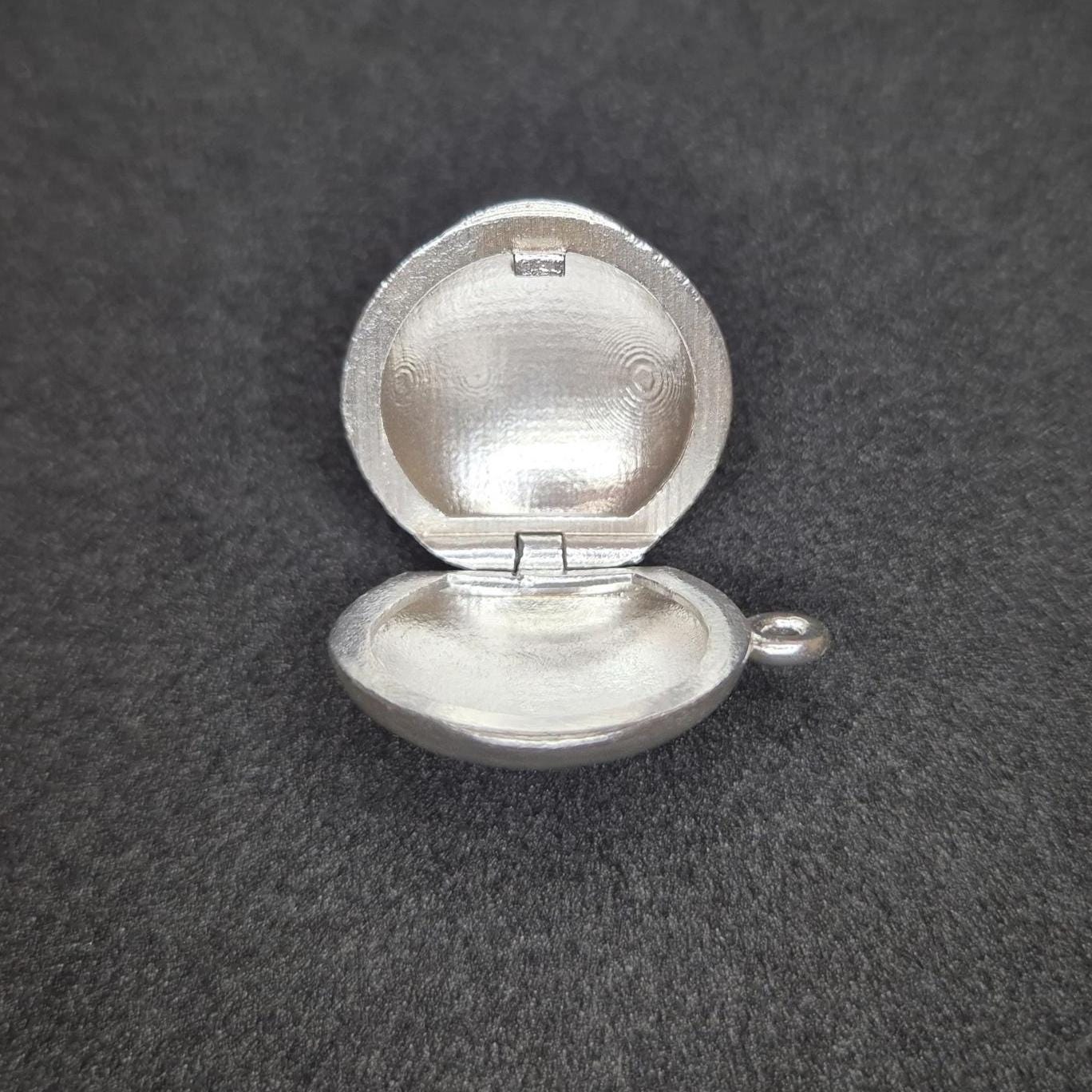 Side View of an Opened Round Silver Locket.