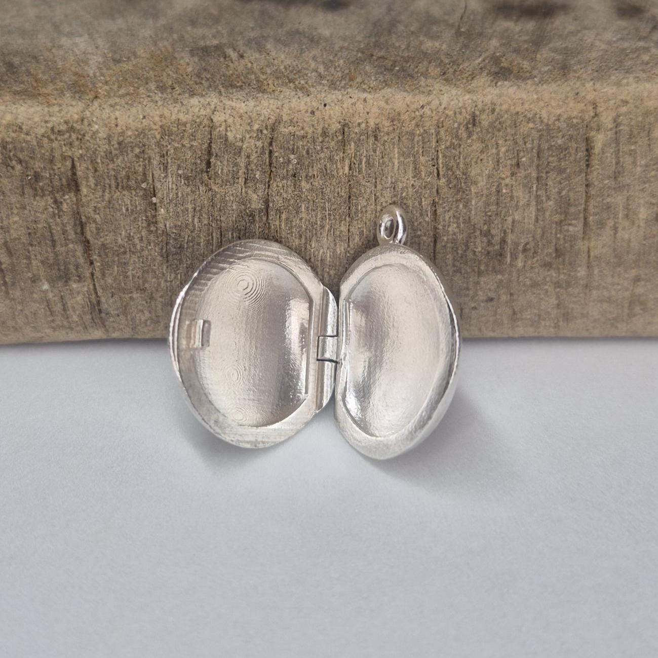 Standing Open Round Silver Locket Against a Wooden Block.
