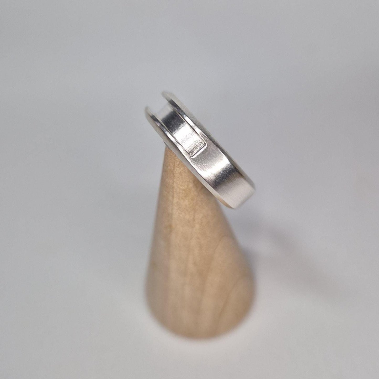 Side angle of a half channel ring on a wooden display cone, highlighting its depth and smooth brushed finish.