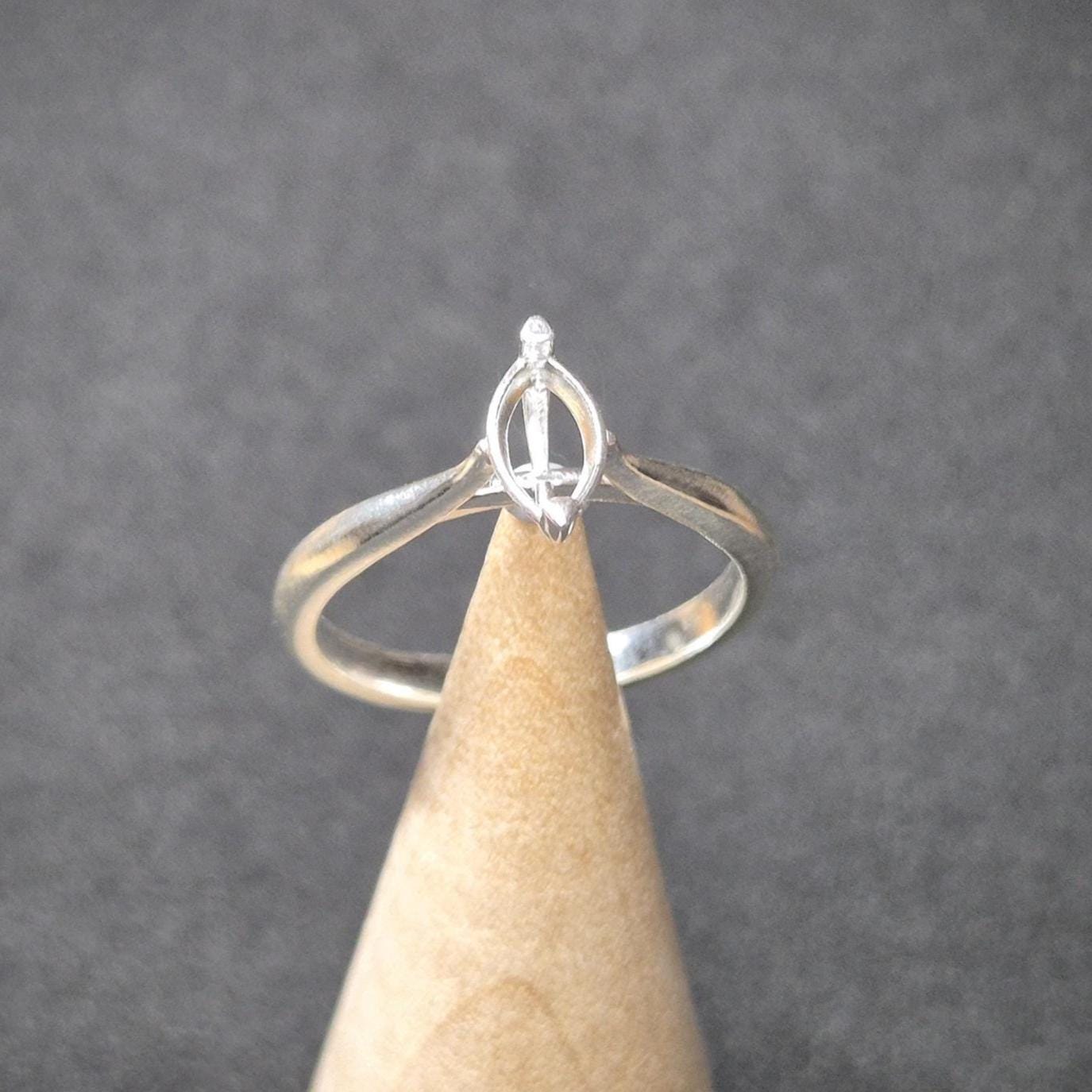 Silver ring blank with marquise setting displayed upright on a wooden ring cone, set against a dark grey backdrop.