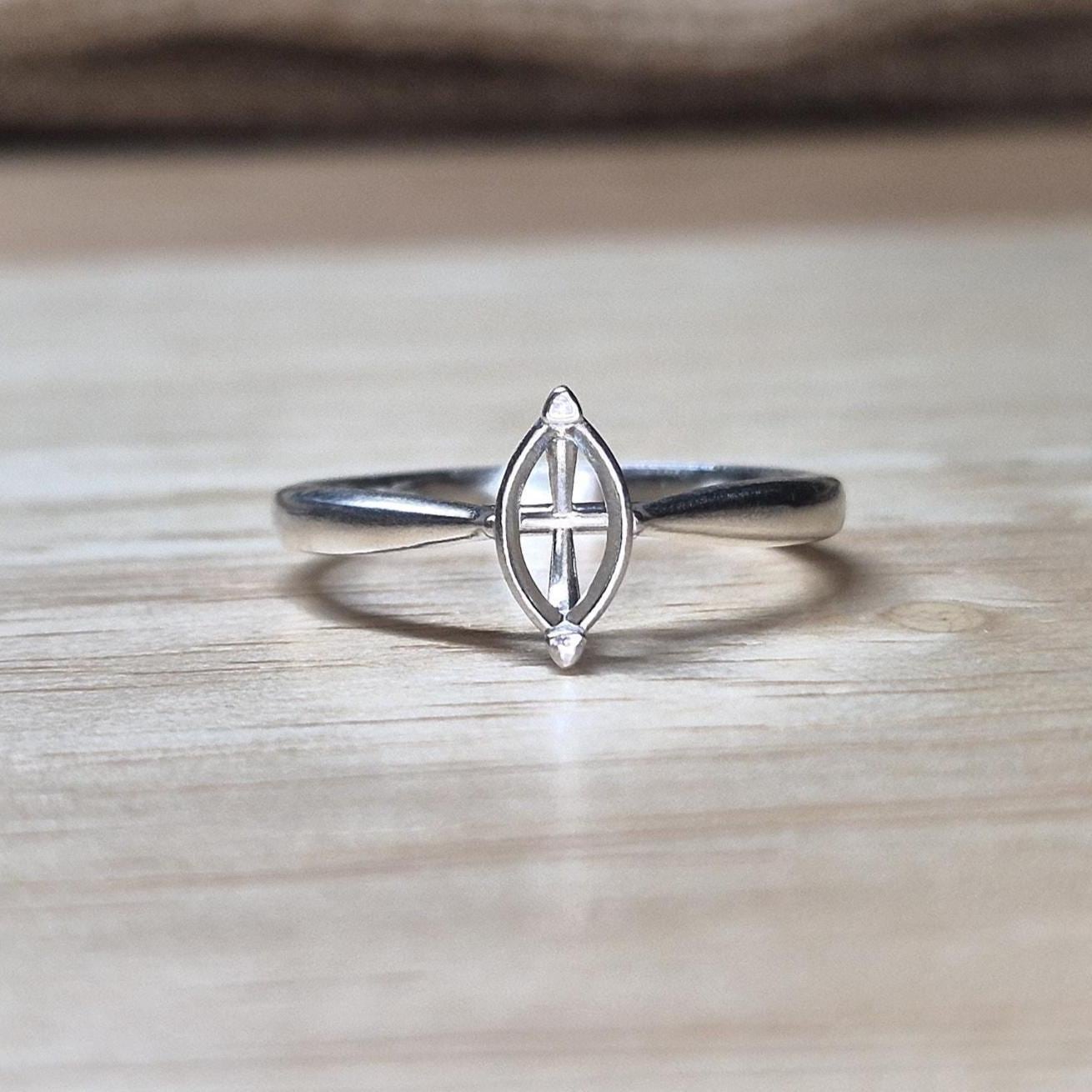 Front-facing shot of a silver ring blank with marquise prongs, ideal for an 8x4mm stone, on a wood backdrop with neutral tones.