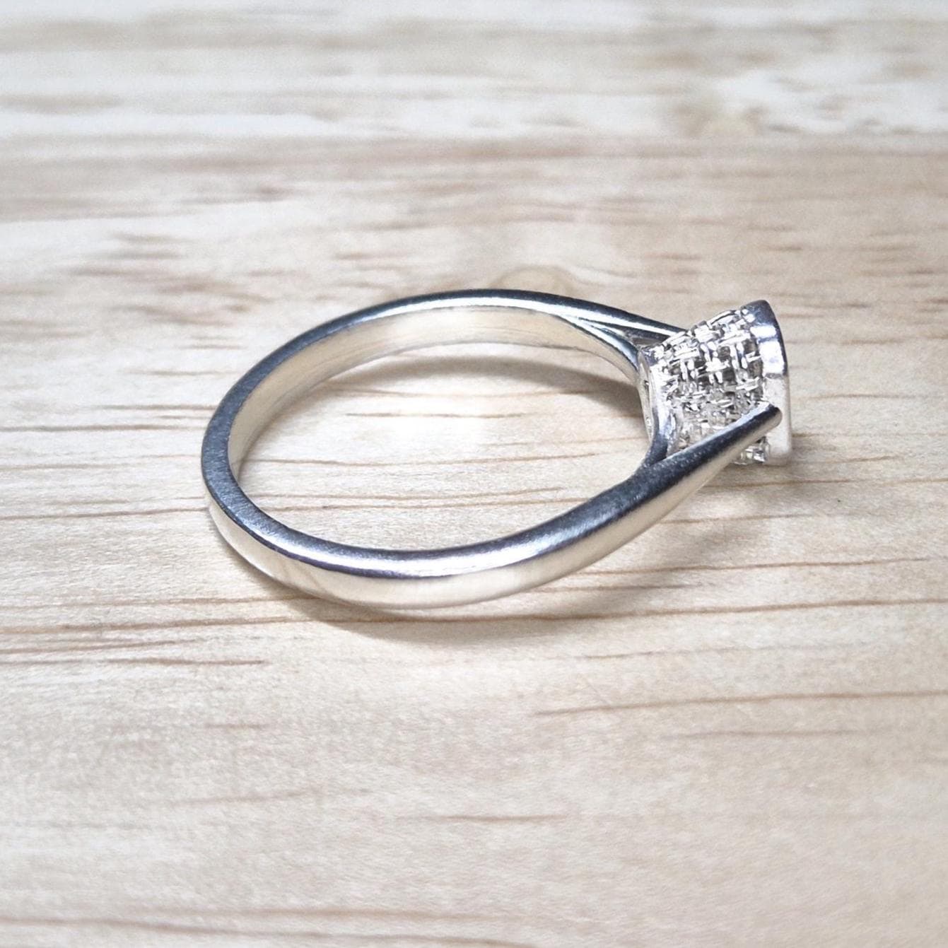 Angled overhead view of an emerald-cut ring blank, with visible cathedral shoulders and structured basket bezel setting.