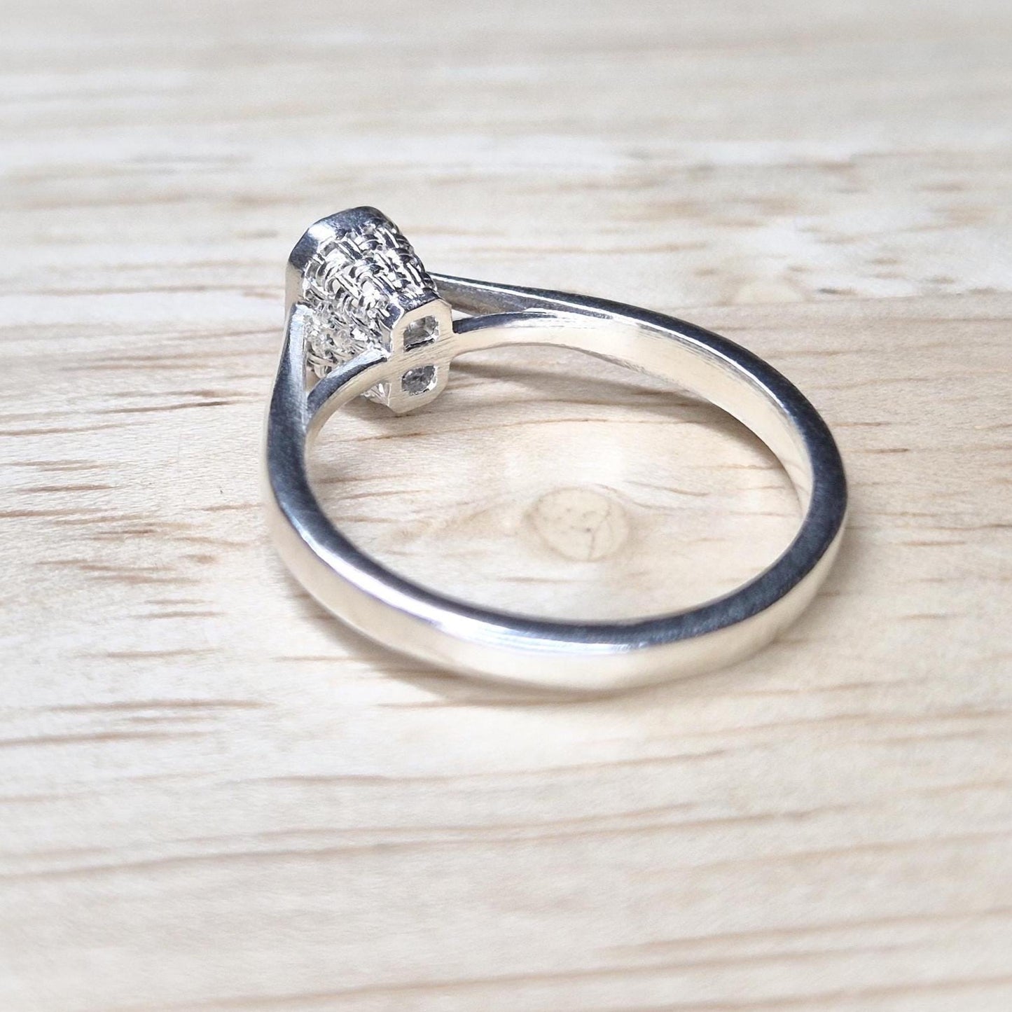 Rear angle of a silver ring blank for emerald cut stones, emphasizing the openwork basket under-gallery.