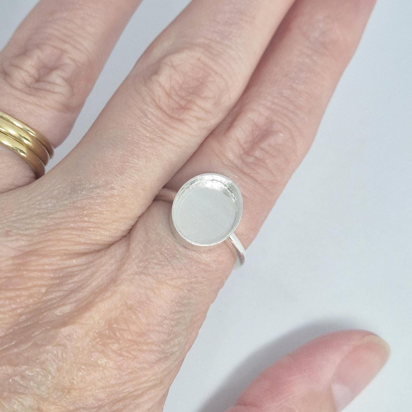 A hand wearing the sterling silver oval cabochon ring setting on the ring finger, demonstrating its size and appearance on a hand. The bezel cup is empty.
