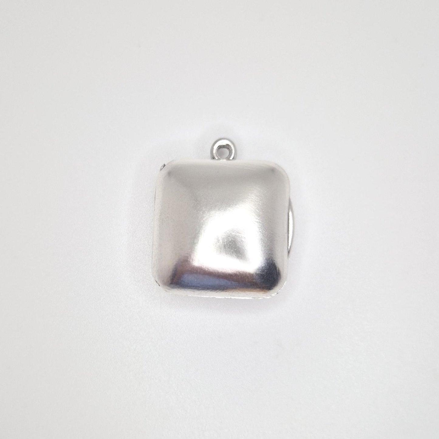 A direct overhead view of a closed sterling silver square locket pendant, showing its polished surface and the small top bail.