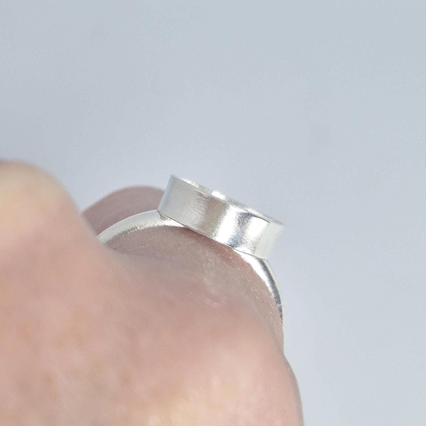 Close-up side profile of a hand holding the oval cabochon ring setting, showing the depth of the empty bezel cup.