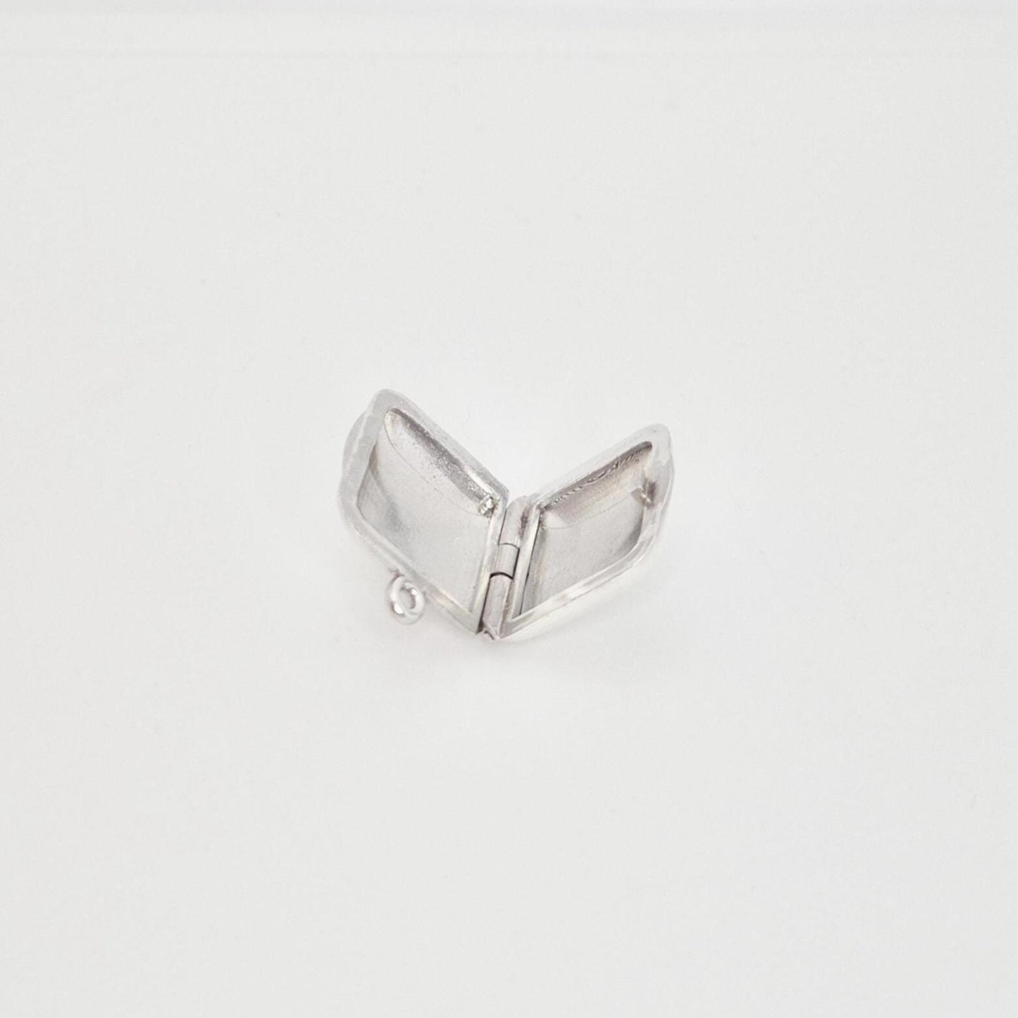 A blank sterling silver square locket pendant opened flat, revealing the two internal compartments and the small ring at the top for attachment, set against a plain white background.