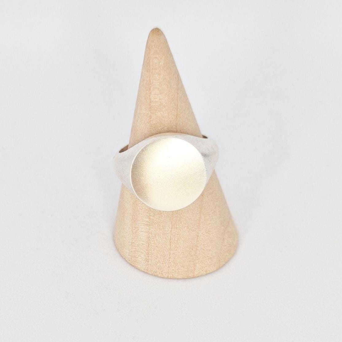 Front view of heavy silver signet ring on cone stand, 16mm blank engraving face