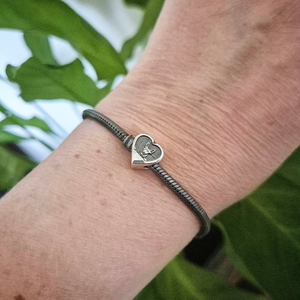 An oxidised silver bracelet on a wrist featuring a dog image.