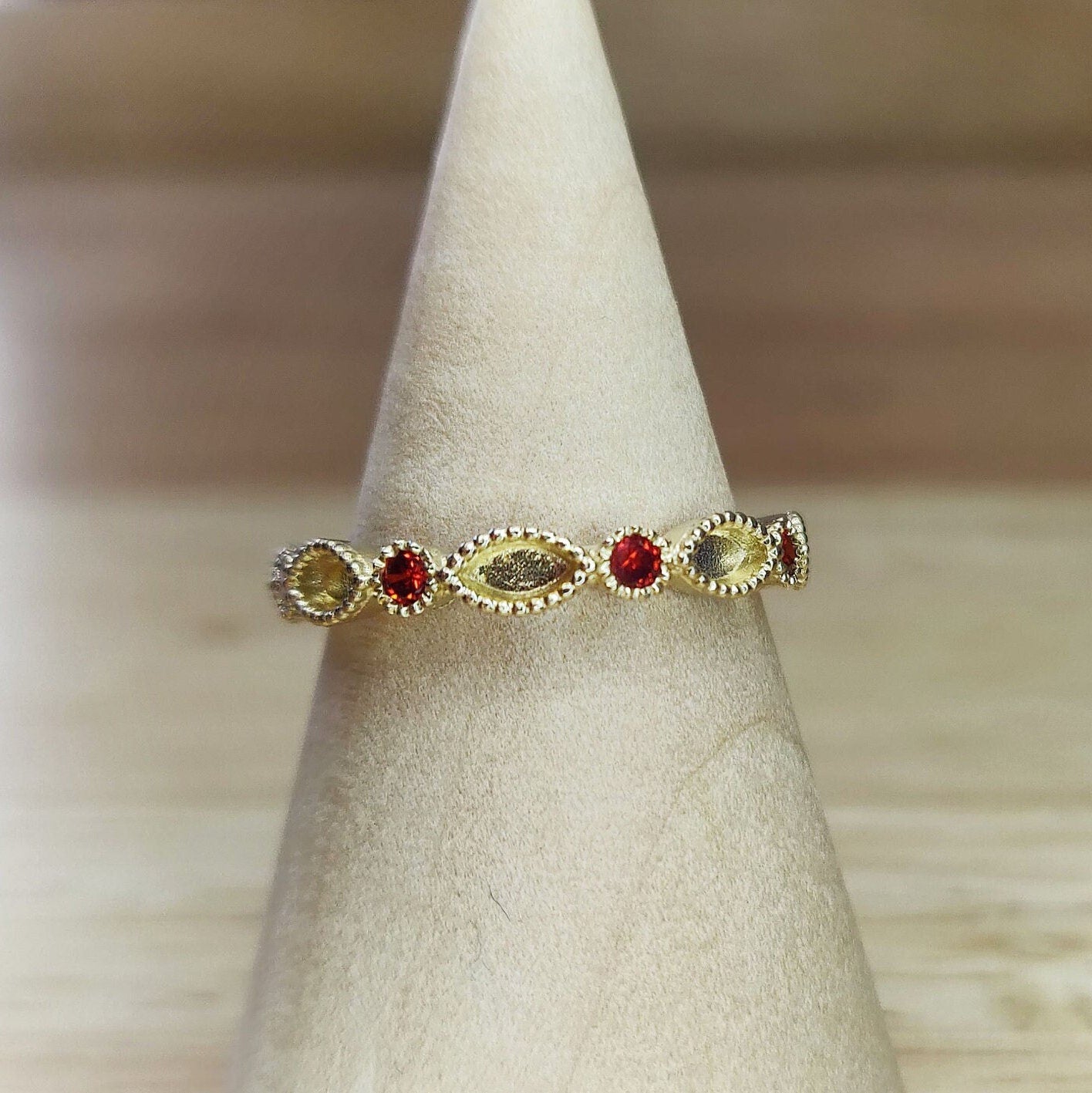 Gold and ruby marquise eternity ring being displayed on a wooden cone.