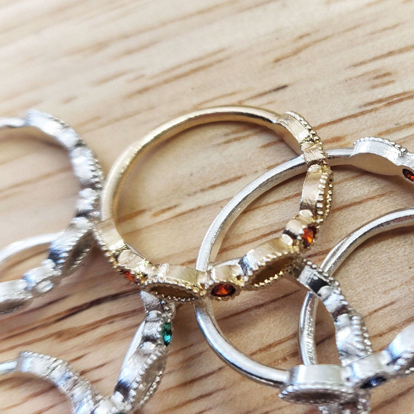 Gold and silver marquise eternity rings with various birthstones, displayed in a pile.