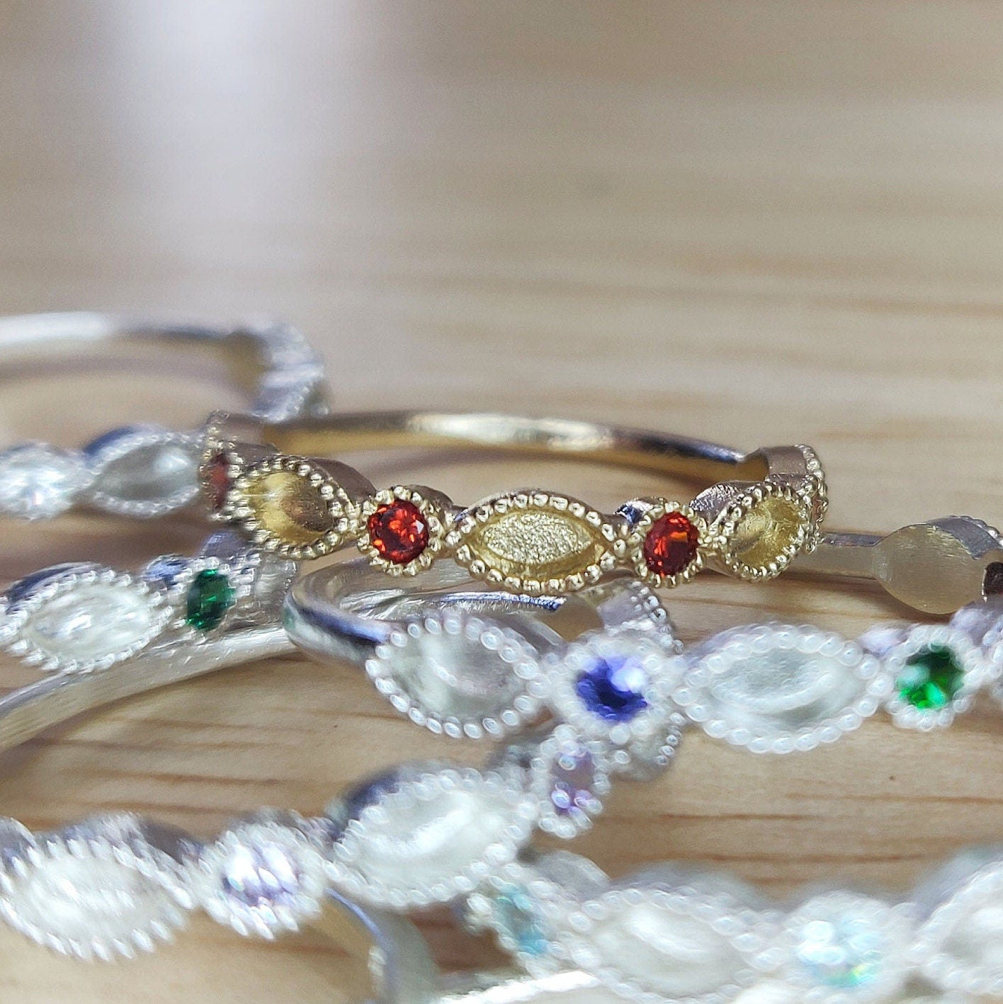 Front view of a selection of gold and silver eternity rings with various birthstones.