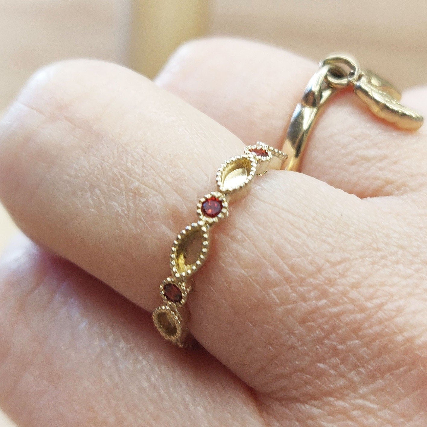 Gold round ad marquise eternity ring being worn on a finger.