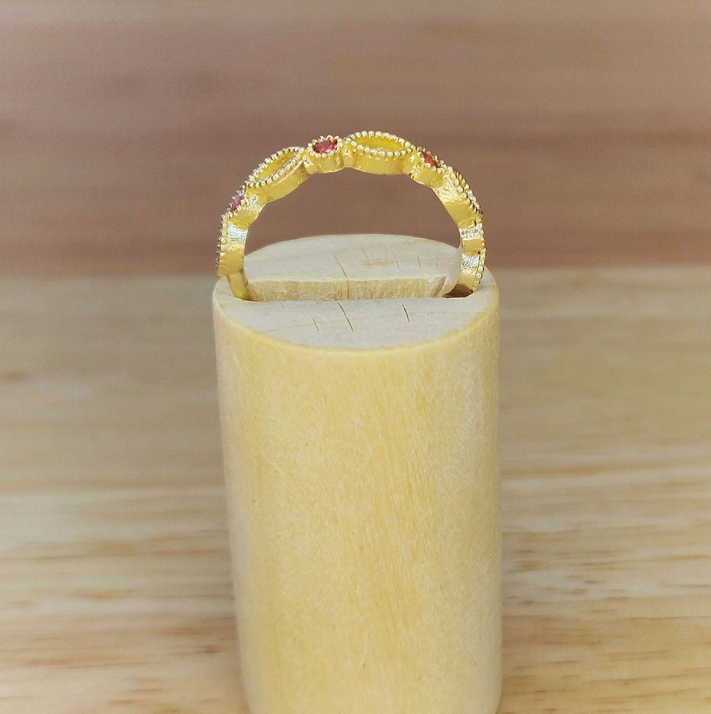 Side view of a gold eternity ring in a wooden stand.