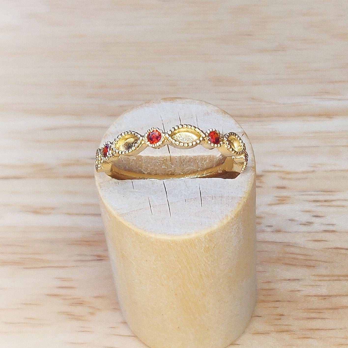 Top view of a dainty gold marquise milgrain eternity ring in a wooden stand.