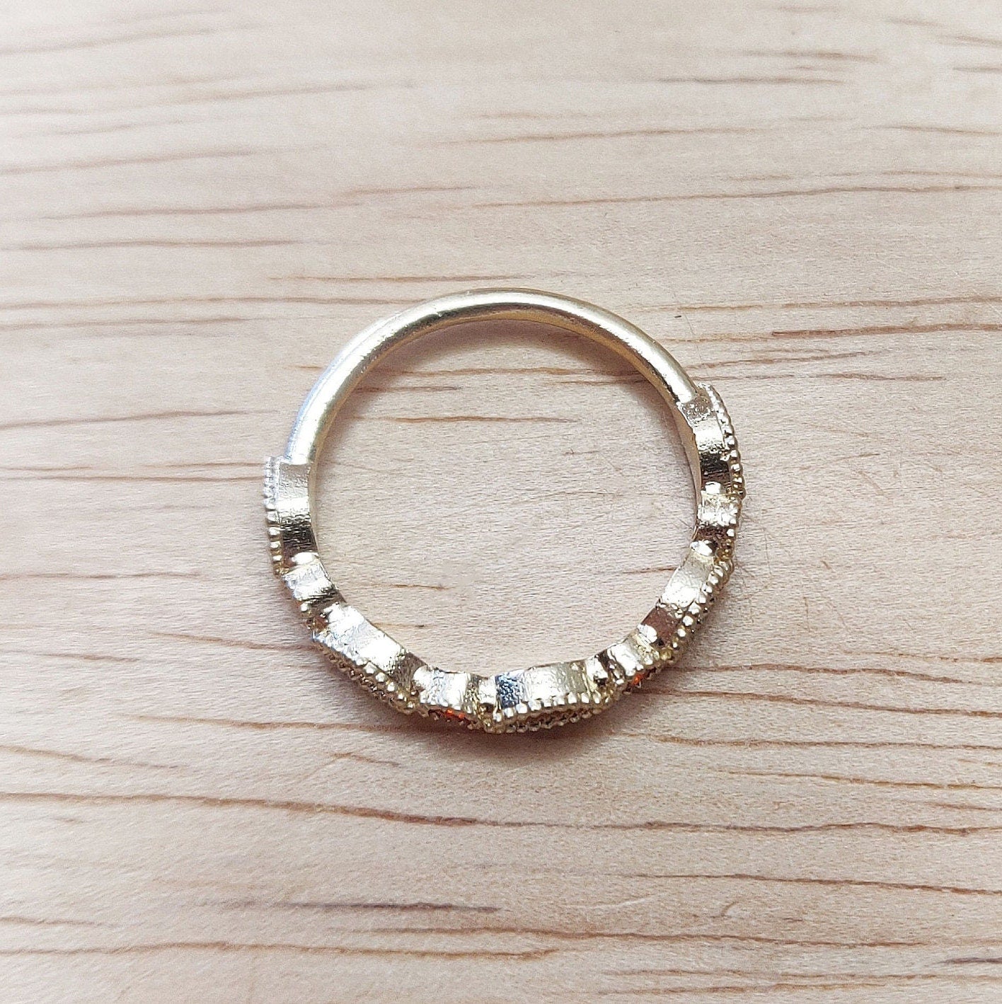 Profile view of a gold birthstone eternity ring on a wooden background.