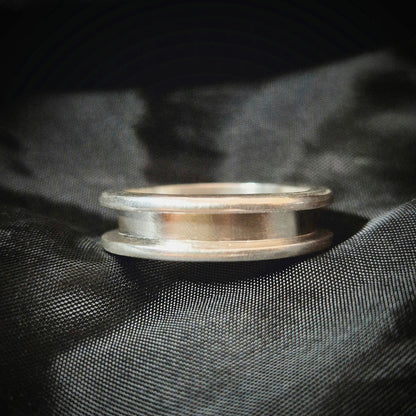 Silver Channel Ring sitting flat on black material background