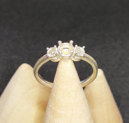 Top view of a 3 stone sterling silver ring with prong settings on a cone