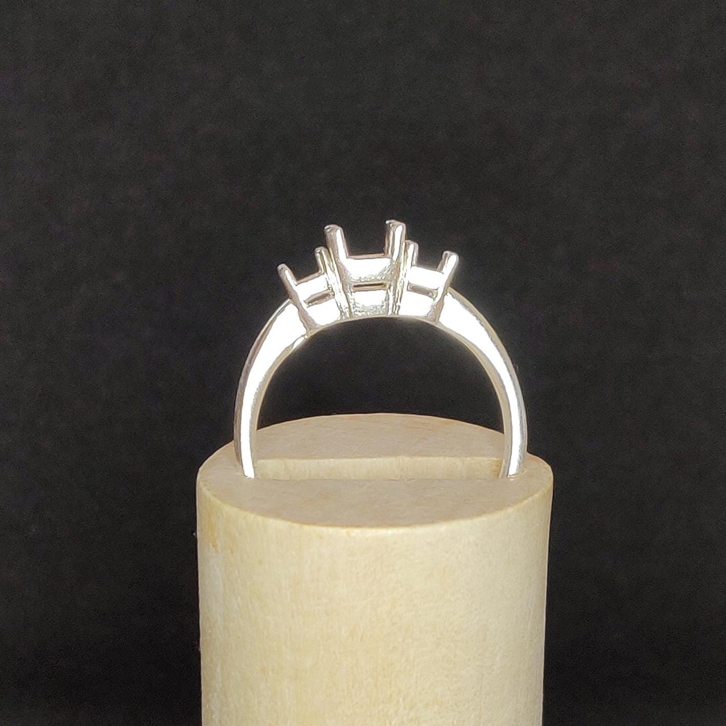 Silver 3 stone claw ring in wooden display.