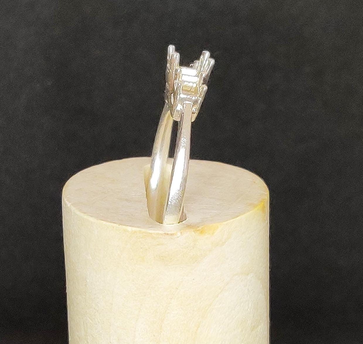 Side view of a silver ring blank in a wooden display block.
