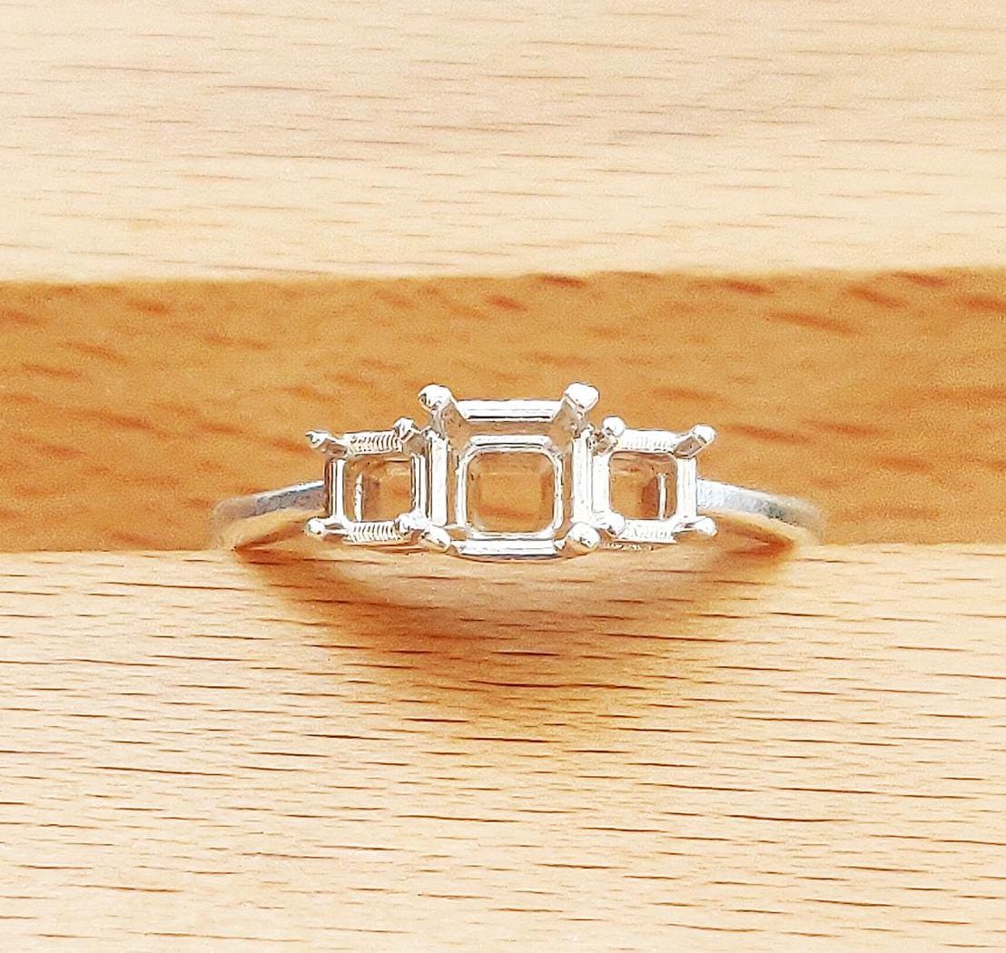 Top view of the gallery prong settings for 3 square gemstones in a wooden block.
