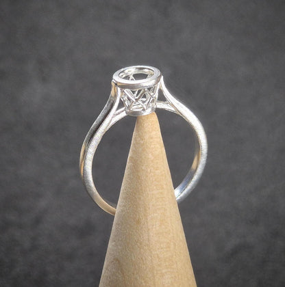 Basket cathedral shank ring in silver balanced on a wooden cone.