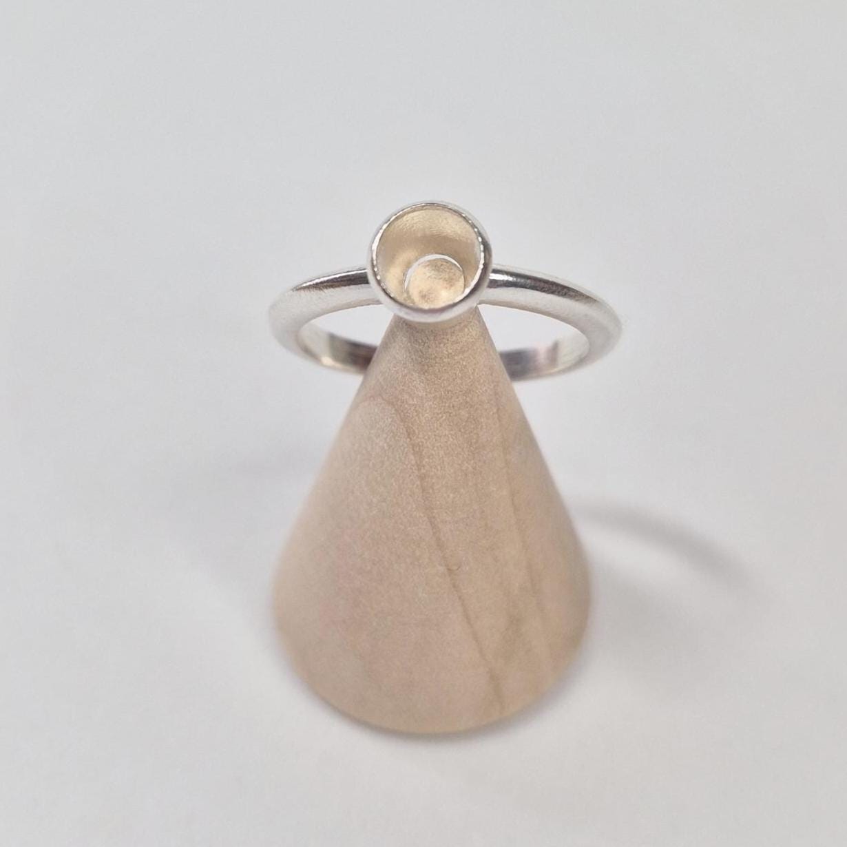 Top View of a Silver Rubover Setting Ring on a Wooden Cone