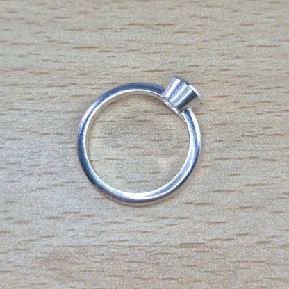Through Ring View of a Silver Rubover Setting Ring on a Wooden Background.
