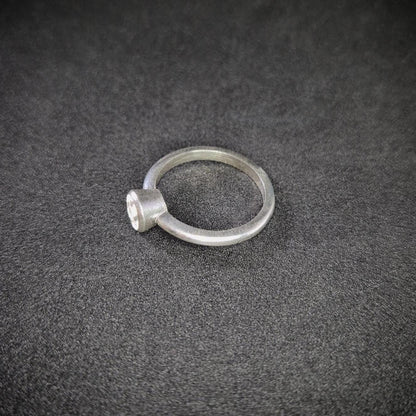 Left View of a Silver Bezel Ring on a Dark Background.